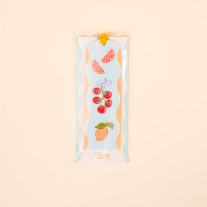 The Darling Effect’s Fruit Market Acrylic Bookmark features vibrant grapefruit, tomato, and pear illustrations—perfect for book lovers or gifting—presented in a clear sleeve on a light beige background.