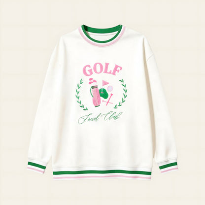 The Darling Effect’s Golf Social Club Oversized Crew features green and pink striped cuffs and collar, a golf-themed embroidered design with "GOLF" in pink letters, a golf ball, flag, and "Social Club" underneath.