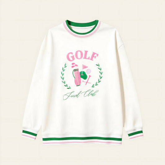 The Darling Effect’s Golf Social Club Oversized Crew features green and pink striped cuffs and collar, a golf-themed embroidered design with "GOLF" in pink letters, a golf ball, flag, and "Social Club" underneath.