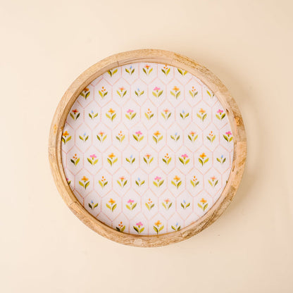 The-darling-effect’s Handpicked For You Large Round Wood Enamel Tray features a white base with colorful floral and green leaf patterns, set against a light beige background for a decorative touch.
