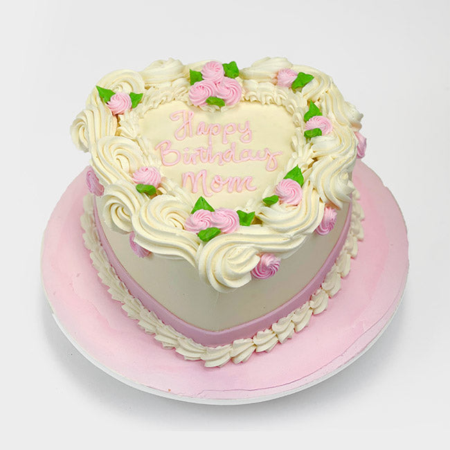 A cream color heart-shaped buttercream Cake, decorated with pink and white rosettes