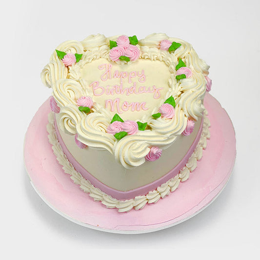 A cream color heart-shaped buttercream Cake, decorated with pink and white rosettes