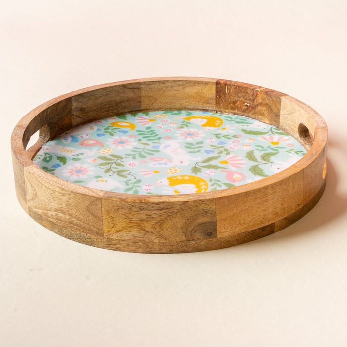 The Hoppy Days Large Round Wood Enamel Tray by the-darling-effect is handcrafted, round, and features cut-out handles plus a floral-patterned base with colorful flowers and leaves on a light background.