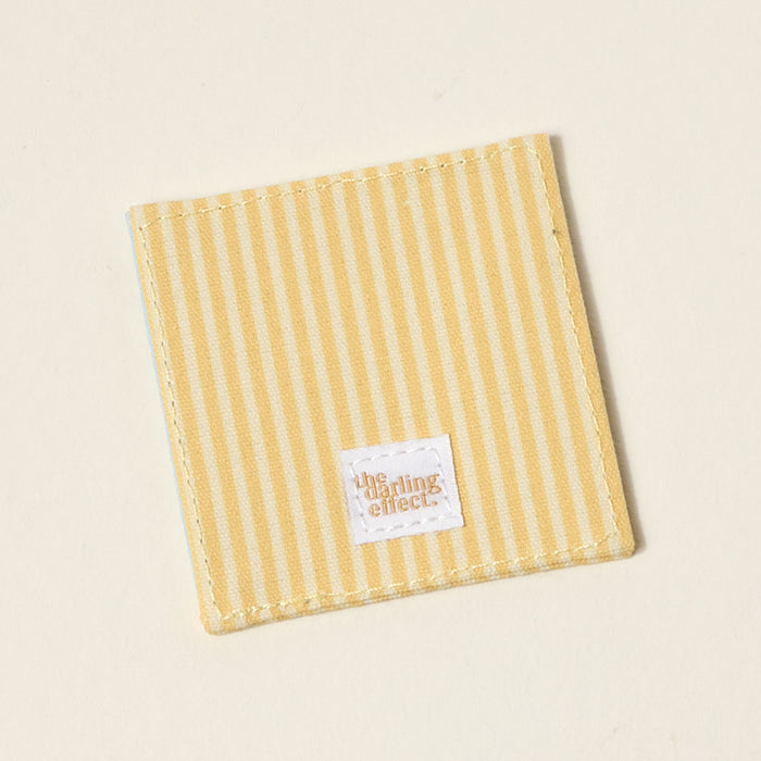 The Darling Effect’s “I’d Rather Be Reading” Corner Keeper Fabric Bookmark features yellow and white stripes with a stitched label, making it a perfect gift for book lovers or a stylish accent for your reading routine.