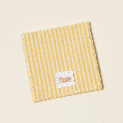 The Darling Effect’s “I’d Rather Be Reading” Corner Keeper Fabric Bookmark features yellow and white stripes with a stitched label, making it a perfect gift for book lovers or a stylish accent for your reading routine.