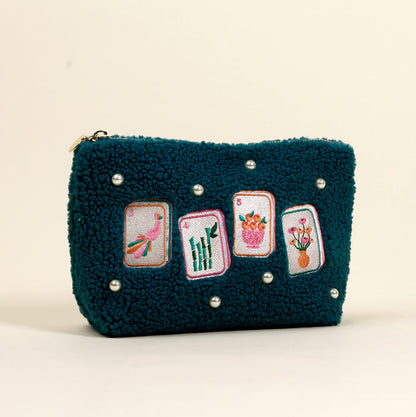 The Darling Effect's It's Mahj Time Teddy Pouch is a teal sherpa bag adorned with faux pearls and embroidered mahjong tiles—bird, bamboo, and flowers—perfectly displayed against a simple light backdrop.
