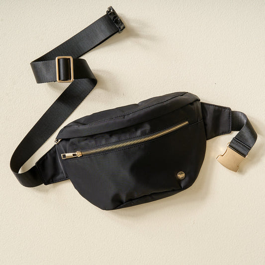 The Darling Effect's Midnight Black XL All You Need Belt Bag features a gold zipper, small round metal logo, and an adjustable black strap with a gold buckle, shown lying flat on a light-colored surface.