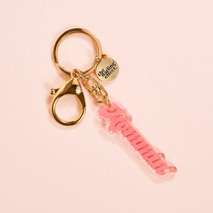 The Darling Effect’s Mommin' Acrylic Keychain features pink acrylic letters on a gold keyring with lobster clasp and a circular charm. This cute accessory is perfect for stylish keychain lovers.