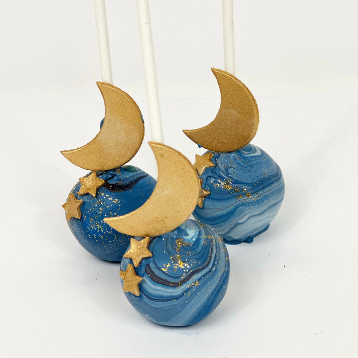 Three blue cake pops decorated with gold fondant moon and stars
