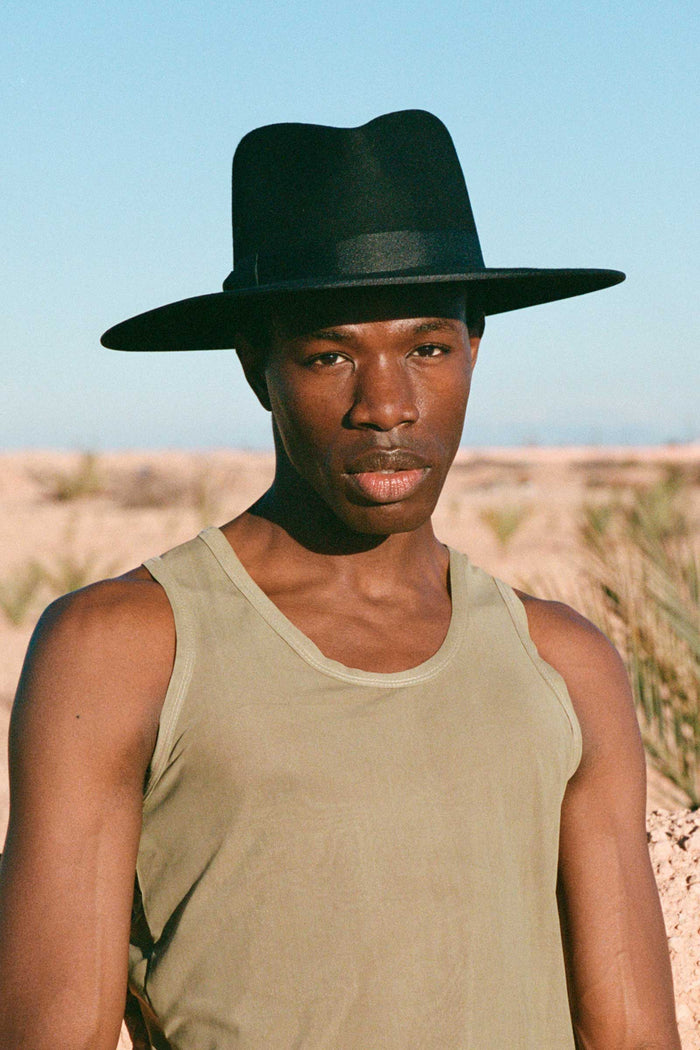 Model wearing Noir Rancher black wool felt fedora hat outdoors