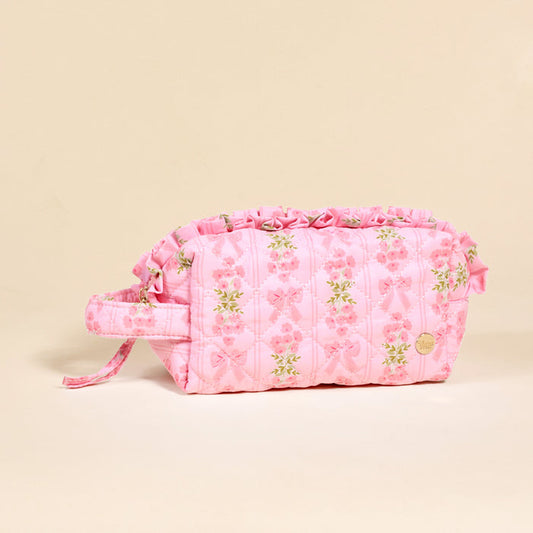 The Darling Effect Oh So Fancy Pink Essentials Quilted Cosmetic Pouch features a floral and bow print with a ruffled top—perfect as a stylish makeup bag or travel pouch.