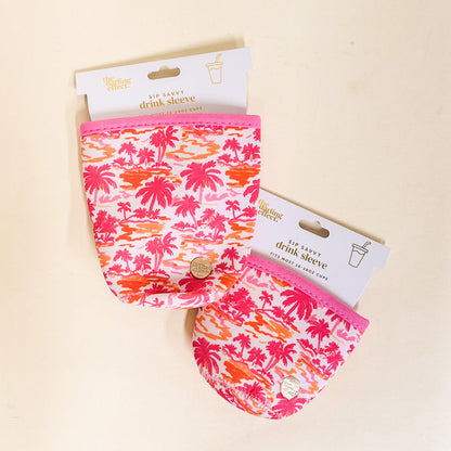 Two Paradise Palms Sip Savvy Drink Sleeves by the-darling-effect, featuring pink and orange tropical palm prints, are shown packaged for mini party cups on a light surface.