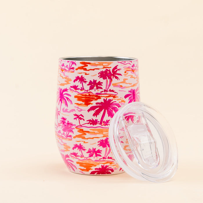 The Darling Effect Paradise Palms Wine Tumbler features a pink and orange palm tree print, triple-wall insulation, and includes a clear spill-resistant lid.