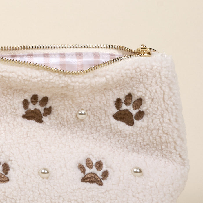 The Darling Effect’s Paws & Pearls Teddy Pouch features a cream sherpa finish with brown paw prints, round pearl-like accents, a gold zipper, and pink and white striped lining—an adorable addition to your teddy pouch collection.
