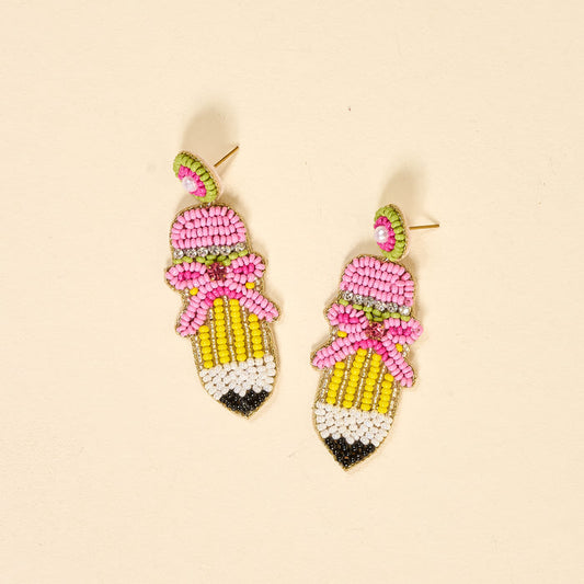 Add a playful touch to your jewelry collection with The Darling Effect's Pencil Me In Beaded Earrings—pencil-shaped, hand-beaded with pink tips, yellow barrels, green beads, and pink bows for extra charm.