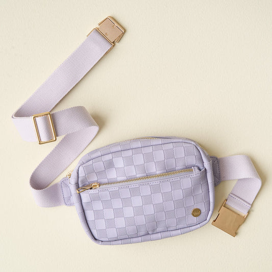 The Darling Effect's Periwinkle Urban Check Belt Bag features light purple checkered vegan leather, a gold zipper, and an adjustable strap, shown against a pale yellow background.