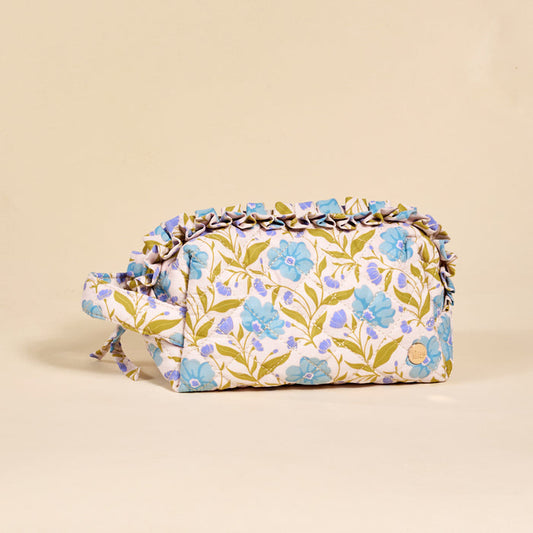 The Darling Effect's Poppin' Petals Aqua Essentials Quilted Cosmetic Pouch features a rectangular design with a handle, blue and green floral pattern, and ruffled trim, displayed against a plain beige background.
