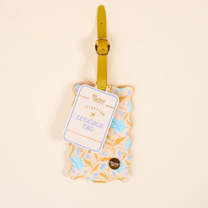The Darling Effect’s Poppin' Petals Aqua Jetsetter Luggage Tag features a yellow strap, scalloped edges, a yellow and blue floral design, privacy flap, and “JETSETTER LUGGAGE TAG” label on a light beige background.