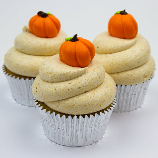 Pumpkin flavored cupcake iced with pumpkin flavored buttercream and topped with a handmade fondant pumpkin