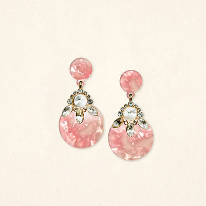 The Darling Effect's Rosé Radiance Show Stopper Earrings feature pink marbled designs with gold accents, clear round crystals, and marquise-shaped crystal details in a floral pattern above the large circle.