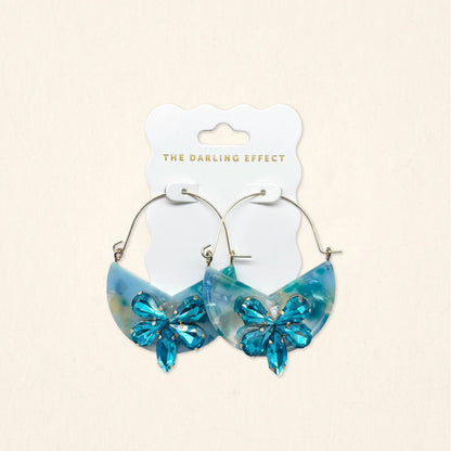 A pair of Sea Glass Marble Bloom Hoop Earrings by The Darling Effect, featuring lightweight hoop design with marble-like accents, displayed on a branded card against a light background.