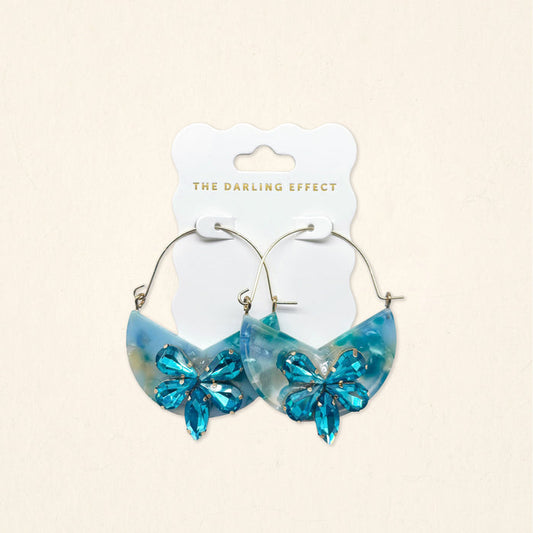 A pair of Sea Glass Marble Bloom Hoop Earrings by The Darling Effect, featuring lightweight hoop design with marble-like accents, displayed on a branded card against a light background.