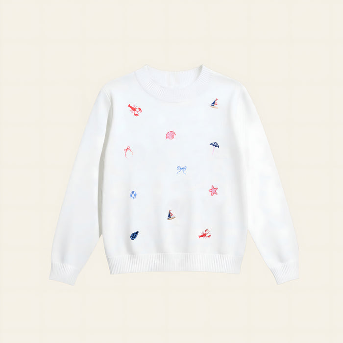 The Darling Effect’s Seaside Haven Refined Knit Sweater is a white crewneck adorned with red embroidered lobsters, blue sailboats and bows, and pink seashells—a charming staple for any wardrobe.