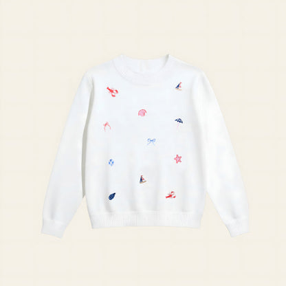 The Darling Effect’s Seaside Haven Refined Knit Sweater is a white crewneck adorned with red embroidered lobsters, blue sailboats and bows, and pink seashells—a charming staple for any wardrobe.