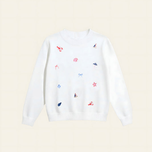 The Darling Effect’s Seaside Haven Refined Knit Sweater is a white crewneck adorned with red embroidered lobsters, blue sailboats and bows, and pink seashells—a charming staple for any wardrobe.