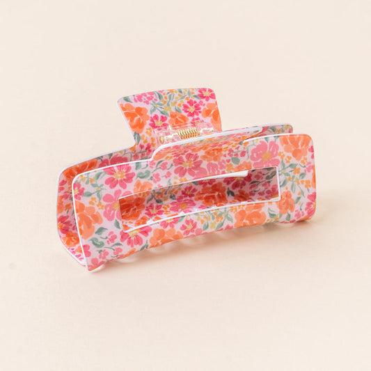The-darling-effect's Secret Garden Pink Claw Clip features pink and orange floral print on a light pink background, adding vibrant color and a secure hold to any hairstyle.