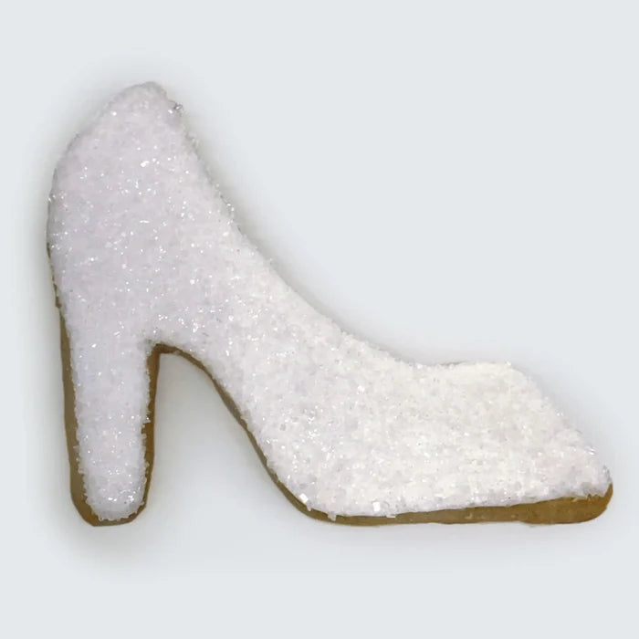 High-heel shoe-shaped sugar cookie decorated with white sparkling sugar crystals on a plain background