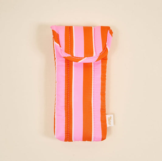 The Darling Effect’s Sicily Stripes Pink Puffy Sunglasses Case features vertical orange and pink stripes, a magnetic flap closure, and a side fabric tag, shown against a plain beige background.