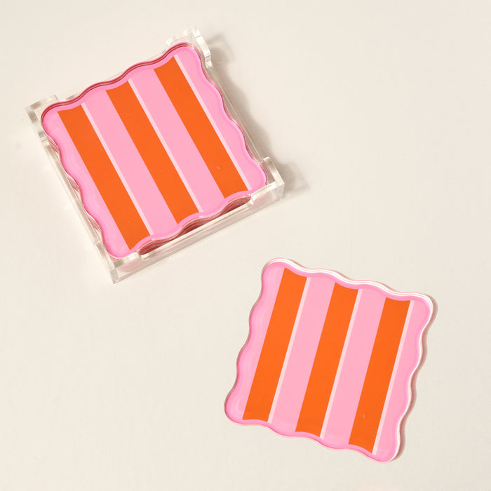 Add a pop of color to your table with The Darling Effect’s Sicily Stripes Pink Table Talk Acrylic Coaster Set—two square coasters with bold pink and orange stripes, wavy edges, and a clear holder for stylish storage.