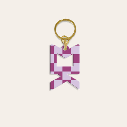 The Darling Effect’s Sigma Kappa Acrylic Keychain features a purple and lilac checkered design in the shape of an M on a gold keyring—ideal as a sorority bid day gift.