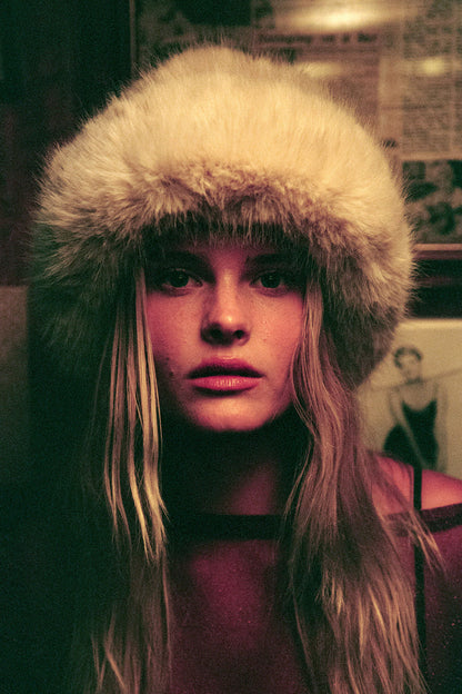 A person wearing a faux-fur bucket hat, styled with long hair.