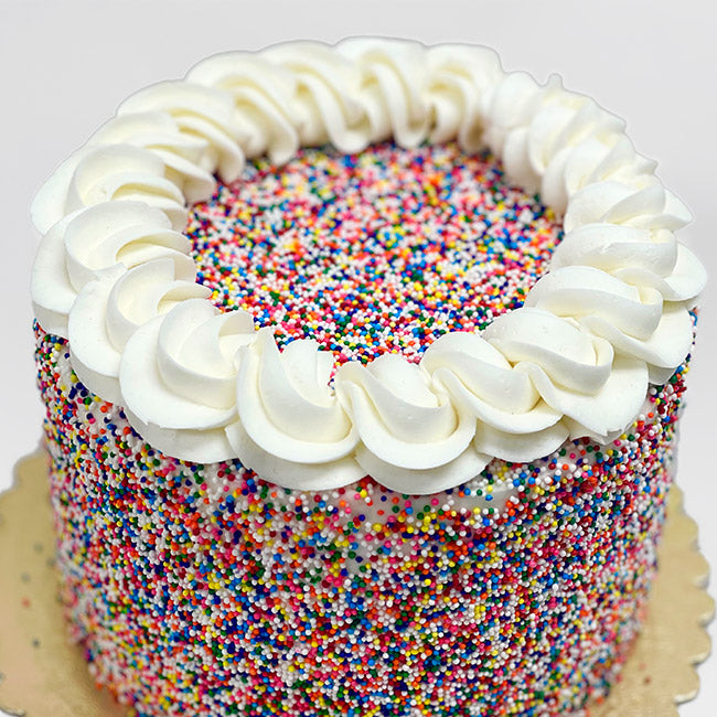 Iced in white buttercream and covered with bright nonpareil sprinkles
