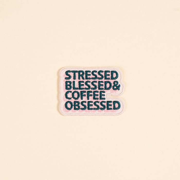 The Darling Effect’s Stressed, Blessed, & Coffee Obsessed Mix & Match Iron-On Patch features dark teal text on pink with a white outline—perfect for customizing jackets or bags with colorful flair.