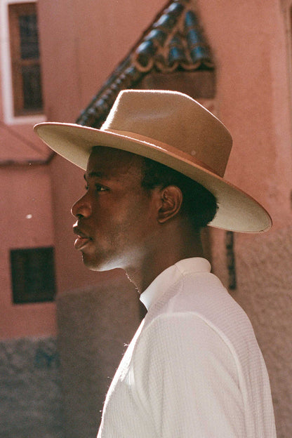 Profile view of a model wearing a Teak Rancher wool felt fedora hat, showcasing its brown color and design.