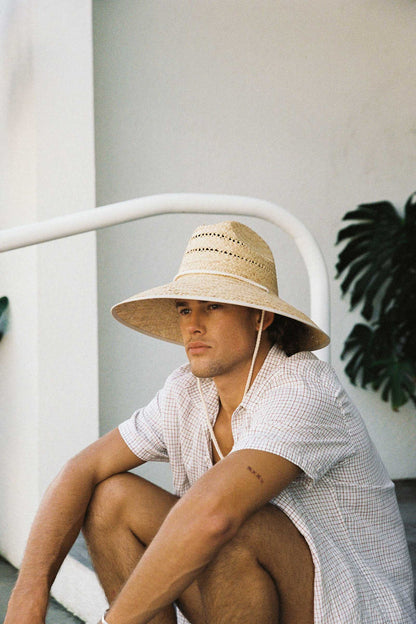 A model wearing The Vista straw cowboy hat, featuring a wide brim and chin strap, ideal for sun protection.
