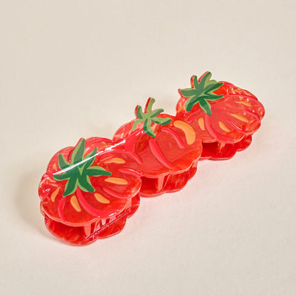 The Darling Effect Tomatoes Shape Up Claw Clip set includes three red tomato-shaped hair accessories with green tops, perfect for cute hairstyles, displayed on a light beige surface.