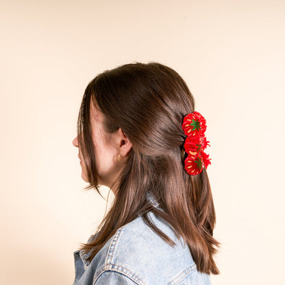 A young person with dark brown hair styled cutely, wearing The Darling Effect's Tomatoes Shape Up Claw Clip as a hair accessory, paired with a denim jacket and a gold hoop earring.