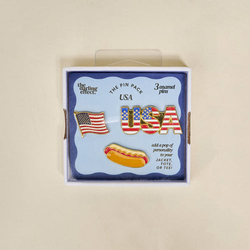 The Darling Effect’s USA The Pin Pack features three collectible pins—an American flag, USA in stars and stripes, and a hot dog—perfect for adding patriotic flair to your jacket, tote, or tee.