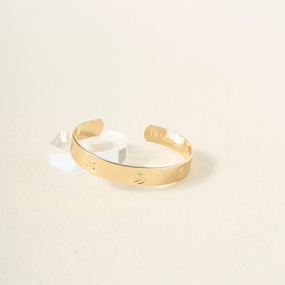 The Darling Effect's You Are A Leader Cuff Bracelet, featuring Pisces zodiac symbols and "PIECES" inscription, sits on a clear acrylic stand against a cream background—an ideal, meaningful gift for astrology enthusiasts.