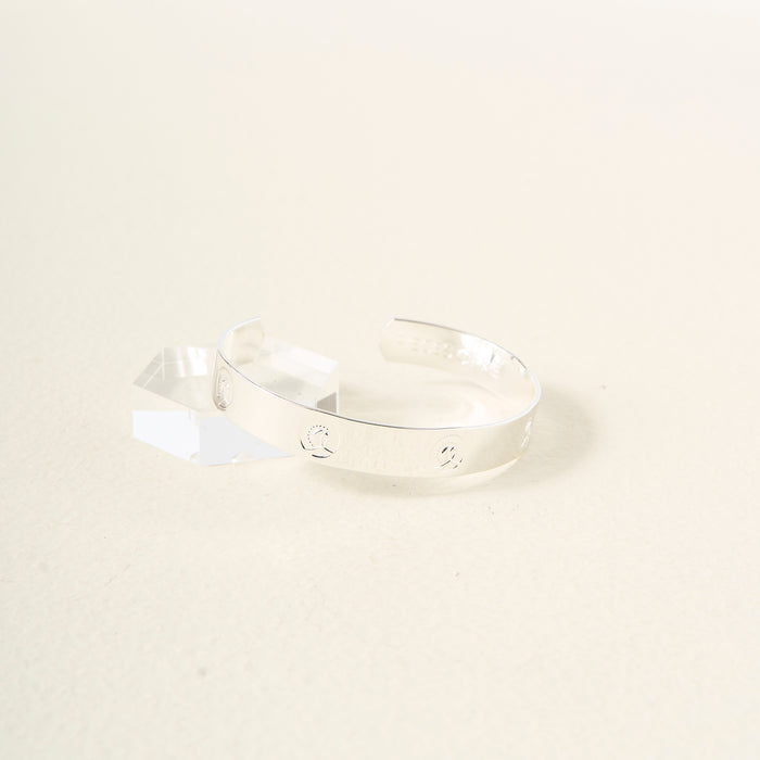 The Darling Effect's "You Are A Leader" cuff bracelet in sterling silver features engraved celestial symbols and text, displayed on a clear acrylic stand against a light background—a stylish and inspiring gift.