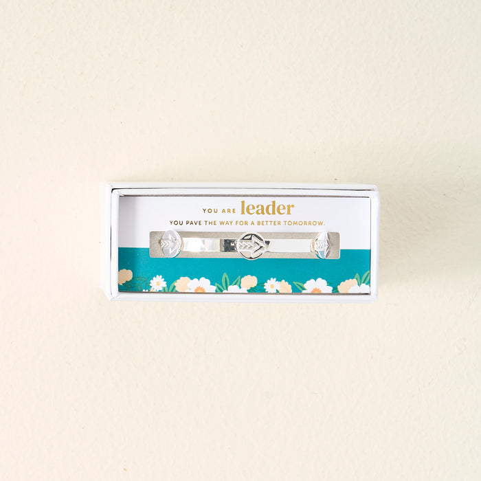 The Darling Effect's "You Are A Leader" Skinny Stacker Trait Bracelet is a silver adjustable cuff, gift-ready in a box with the message: "You are leader. You pave the way for a better tomorrow." Box has teal floral accents.