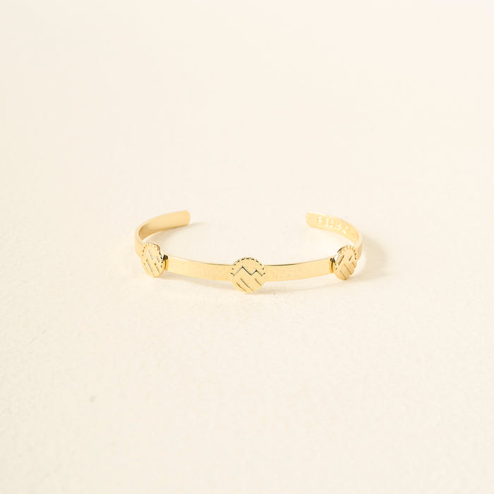 The Darling Effect’s You Are Adventurous Skinny Stacker Bracelet is a 14k gold-plated adjustable cuff with three round zigzag-engraved accents, shown on a simple light background.