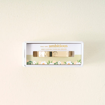 A meaningful gift, the You Are Ambitious Cuff Bracelet by The Darling Effect comes in a white box with floral designs and the inspiring words "You are ambitious. Keep chasing those big dreams." printed above the bracelet.