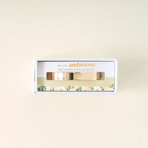 A meaningful gift, the You Are Ambitious Cuff Bracelet by The Darling Effect comes in a white box with floral designs and the inspiring words "You are ambitious. Keep chasing those big dreams." printed above the bracelet.