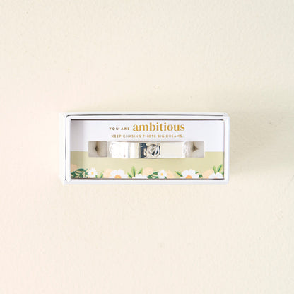The Darling Effect's You Are Ambitious Cuff Bracelet, a sterling silver piece with a floral design and uplifting message on the box, is set against a simple background—an inspiring and meaningful gift.