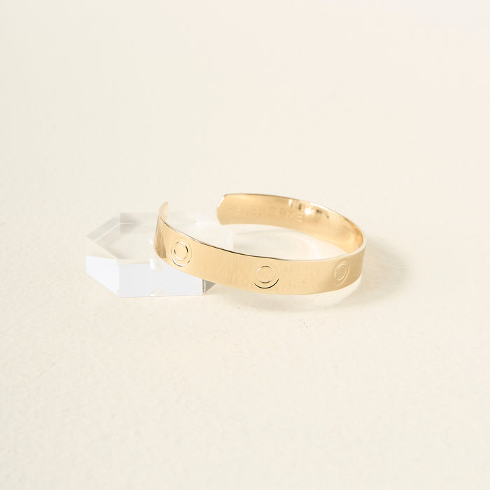 The Darling Effect’s You Are Bold Cuff Bracelet, crafted in sterling silver with engraved circular patterns, is showcased on a faceted clear block against a soft background—an ideal choice for a meaningful gift.